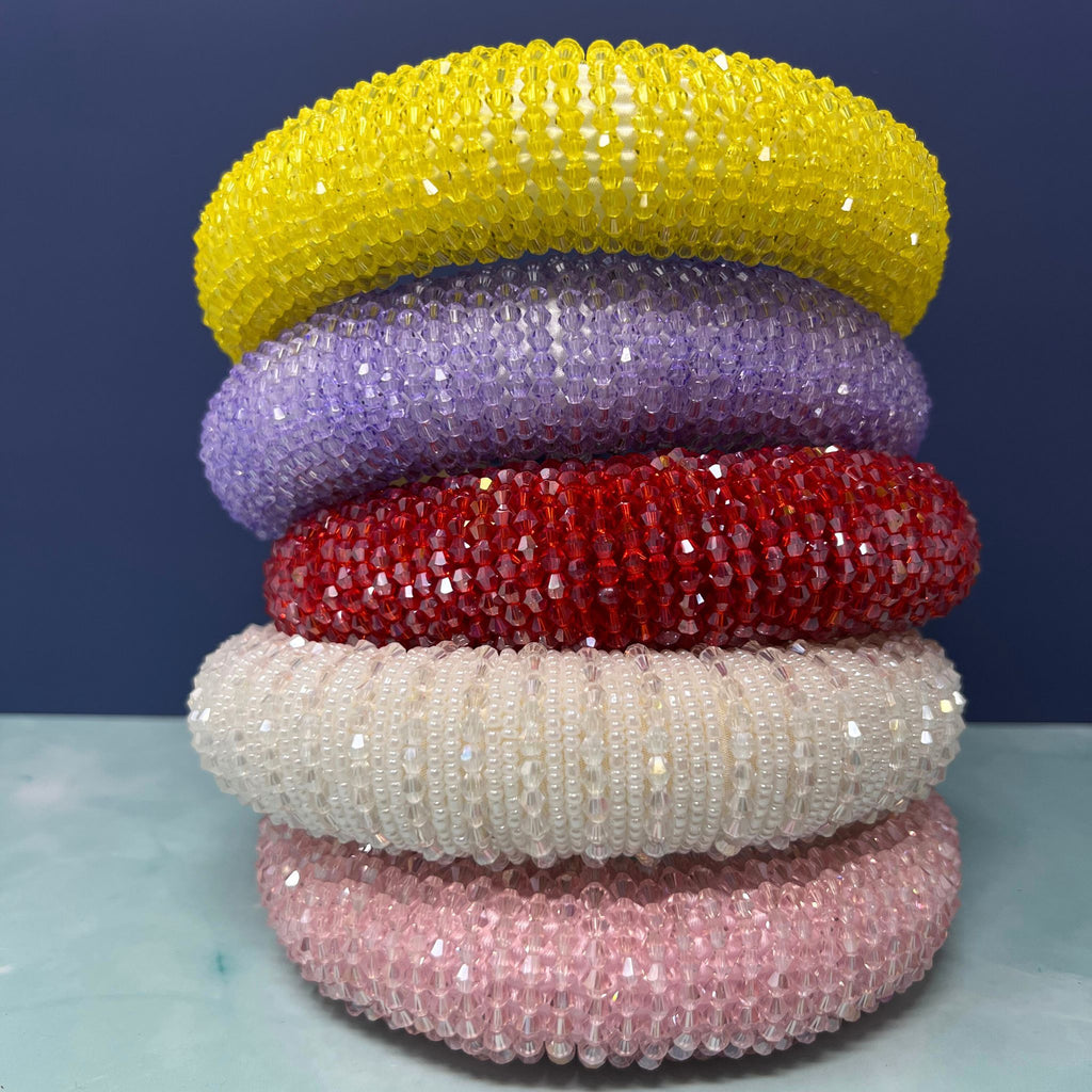 "Stack of sparkly crystal beaded headbands in red, white, pink, purple, and yellow on display"