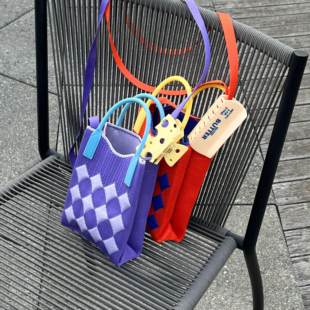 Jacquard knit mini tote bag with a harlequin diamond pattern, rubber handles, and a tuckable shoulder strap