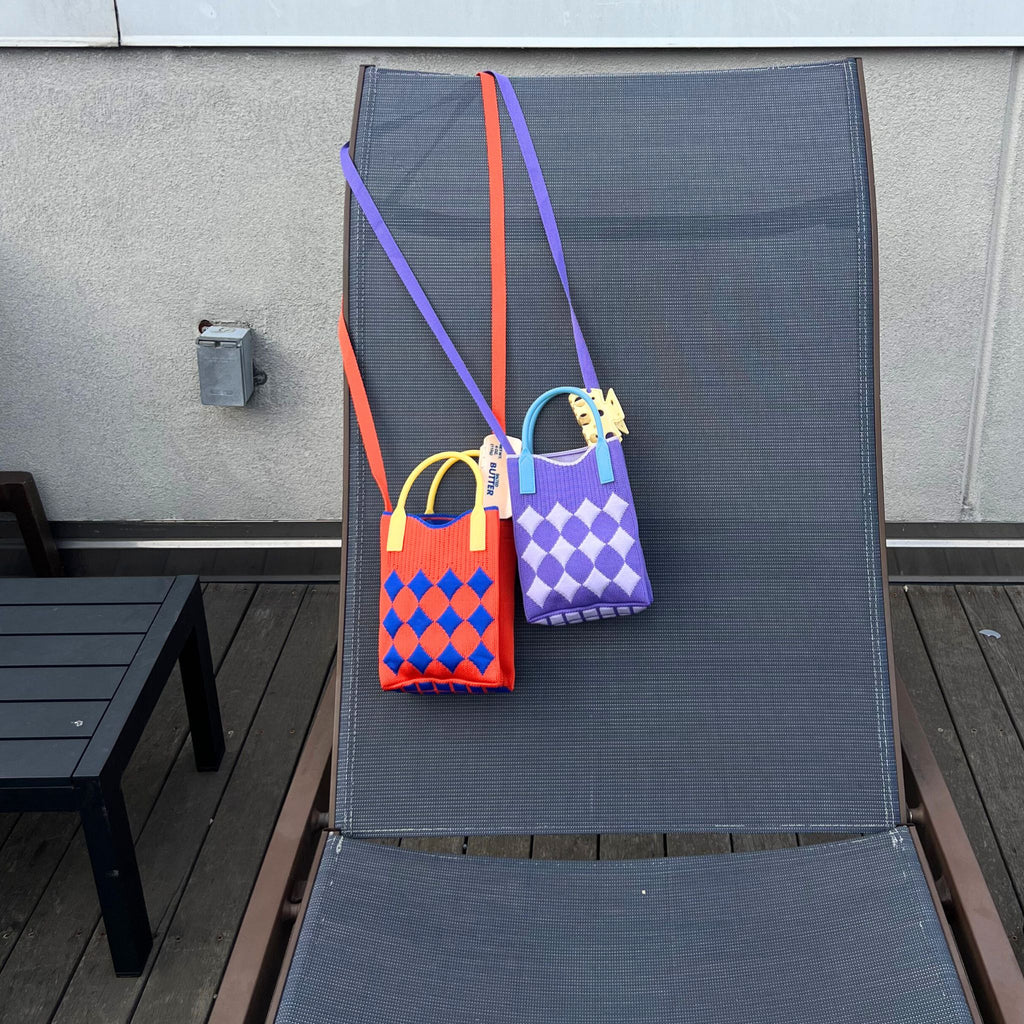 Jacquard knit mini tote bag with a harlequin diamond pattern, rubber handles, and a tuckable shoulder strap