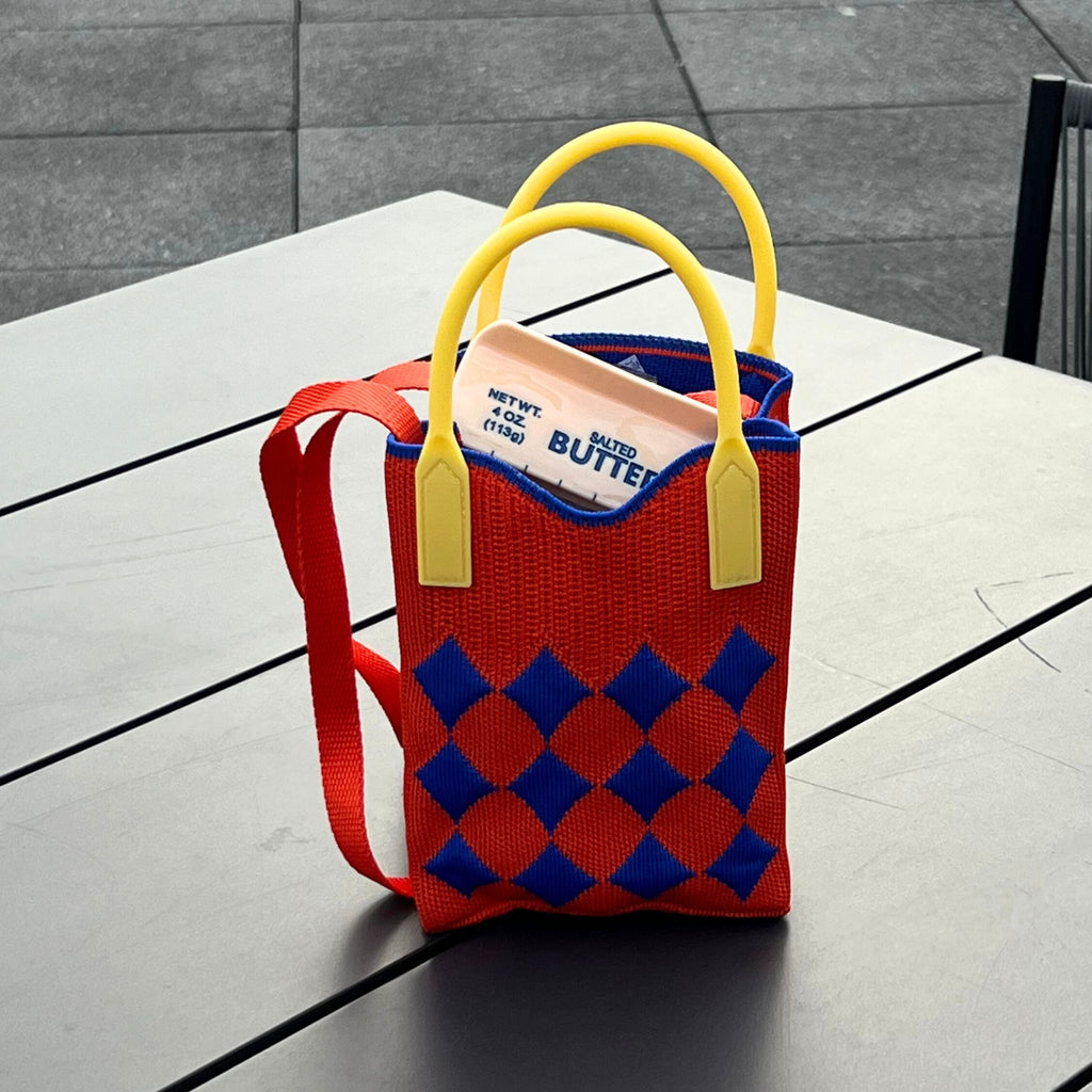 Jacquard knit mini tote bag with a harlequin diamond pattern, rubber handles, and a tuckable shoulder strap