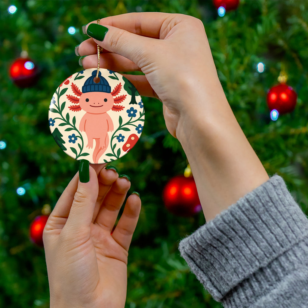 Hand holding a decorative ornament with a cartoon character against a Christmas tree background