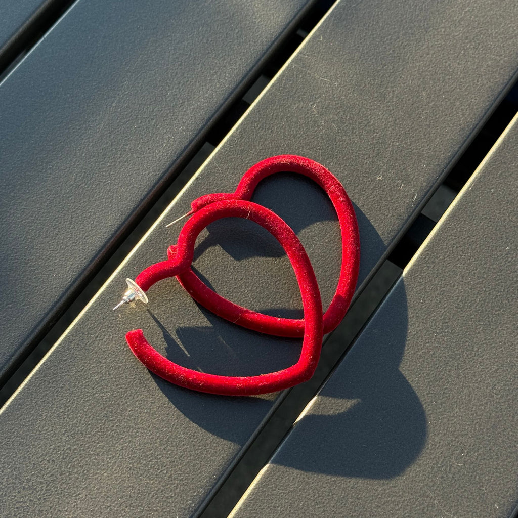 Red heart-shaped earrings on a metallic surface