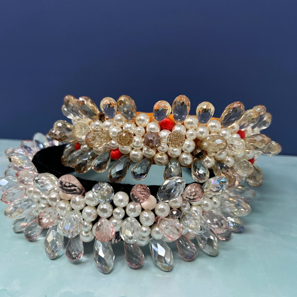 Two ornate headbands with crystal teardrops, faux pearls, and colorful beaded details arranged in floral patterns on a padded base.