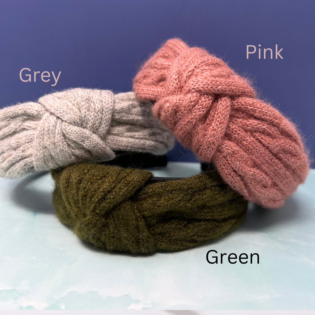 "Chunky knit headbands in blush pink, sage green, and cream stacked in a cozy trio"