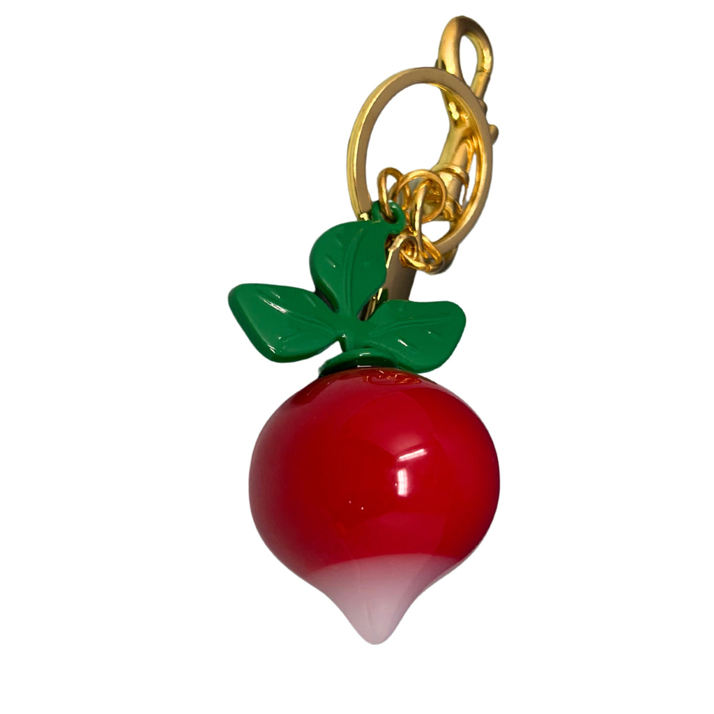 Radish keychain with glossy red root, white tip, green enamel leaves, and gold hardware displayed against a light background