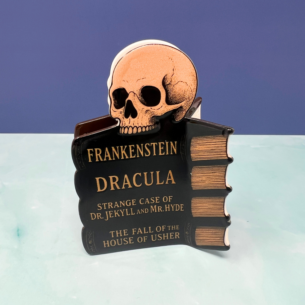 Halloween hair claw clip featuring classic horror book spines like Dracula and Frankenstein on a black claw background

