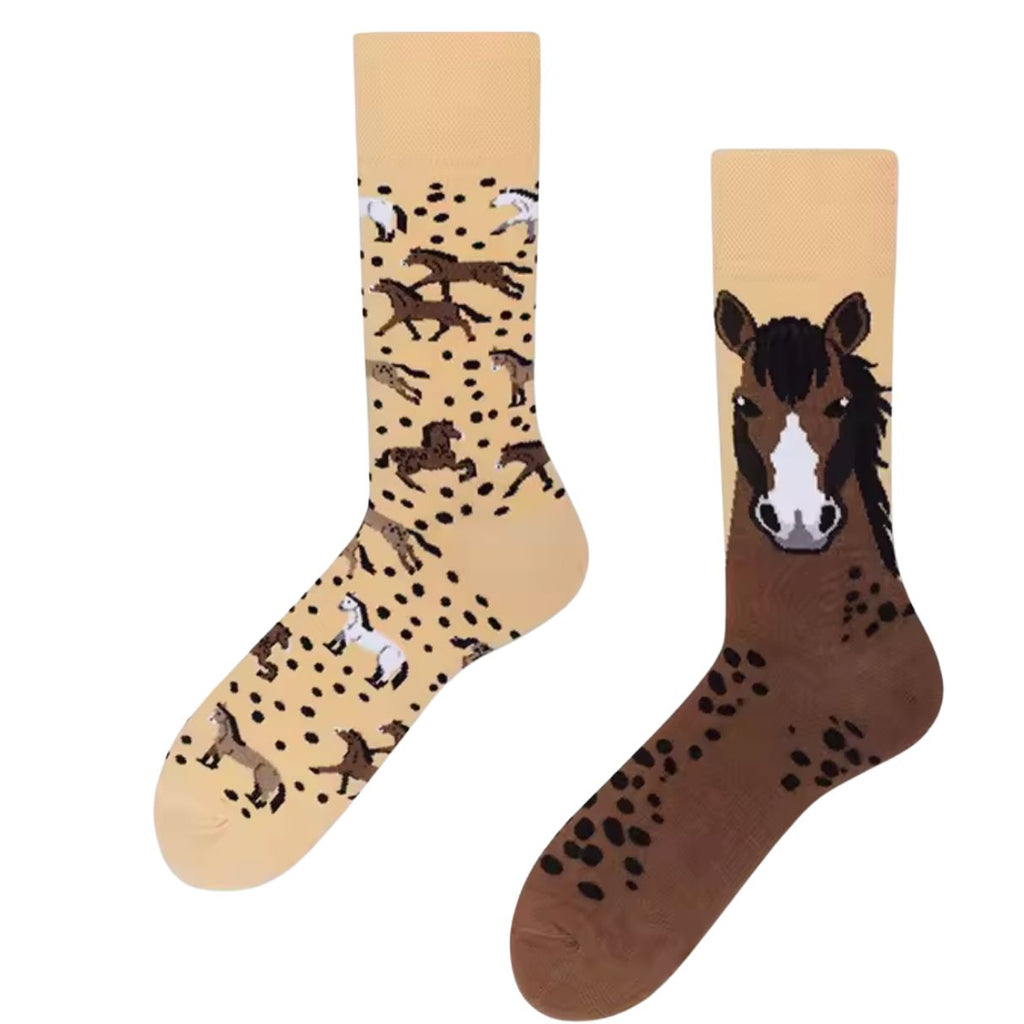 Pair of mismatched socks—one with galloping horses and one with a large horse face—set on a beige background with scattered dark spots.