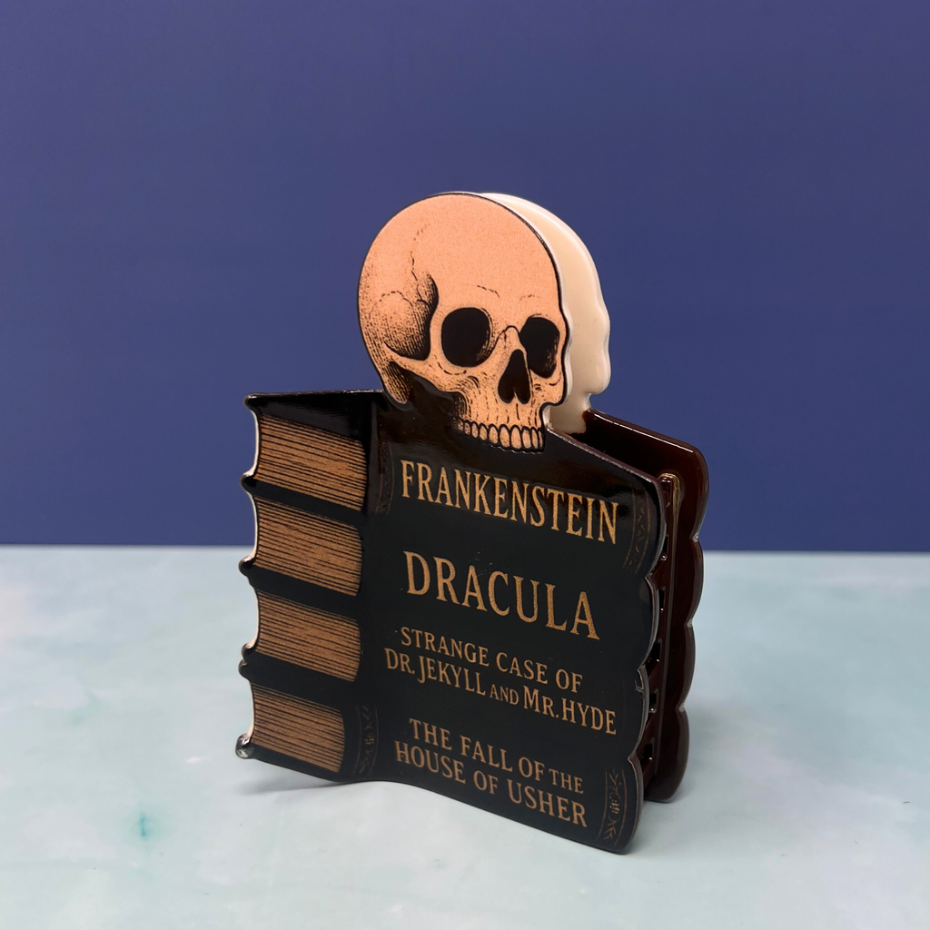 Halloween hair claw clip featuring classic horror book spines like Dracula and Frankenstein on a black claw background

