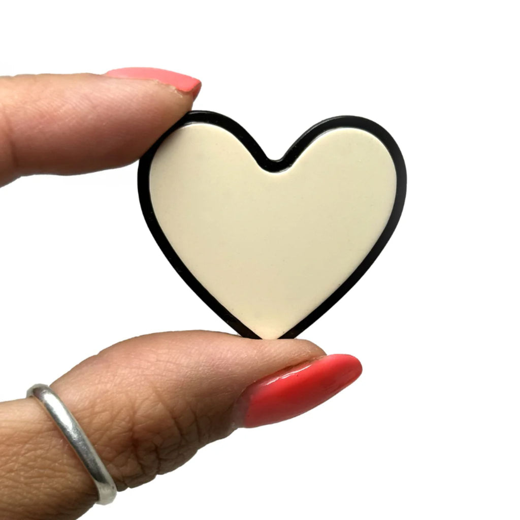Set of two monochrome heart-shaped hair clips—one black with white outline, one white with black outline—featuring secure alligator clip backing, measuring 1.5 inches wide by 1.75 inches high.