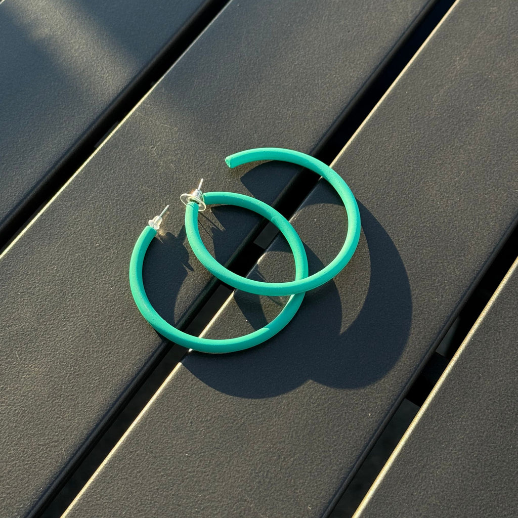 Turquoise hoop earrings on a dark wooden surface