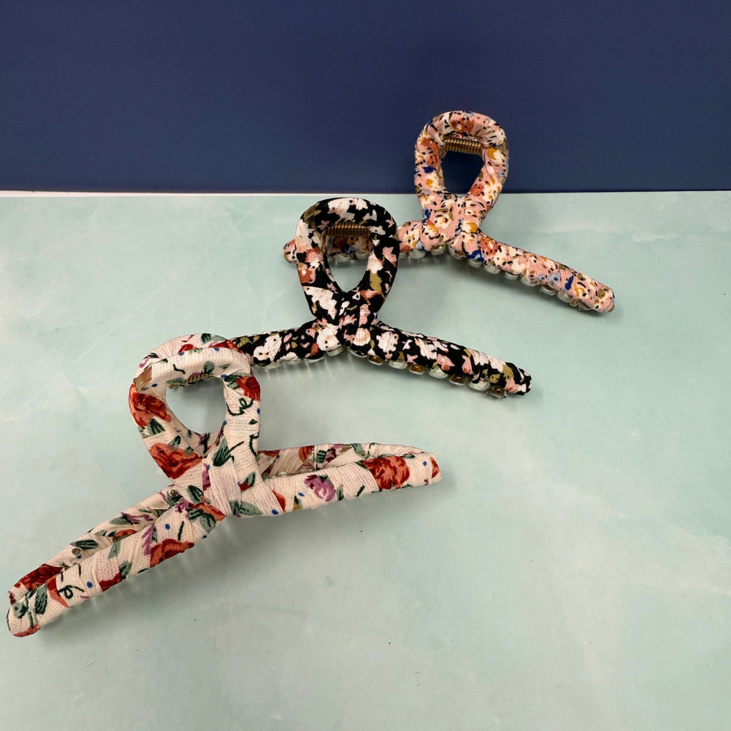Three floral-patterned hangers on a light blue surface with a dark blue background