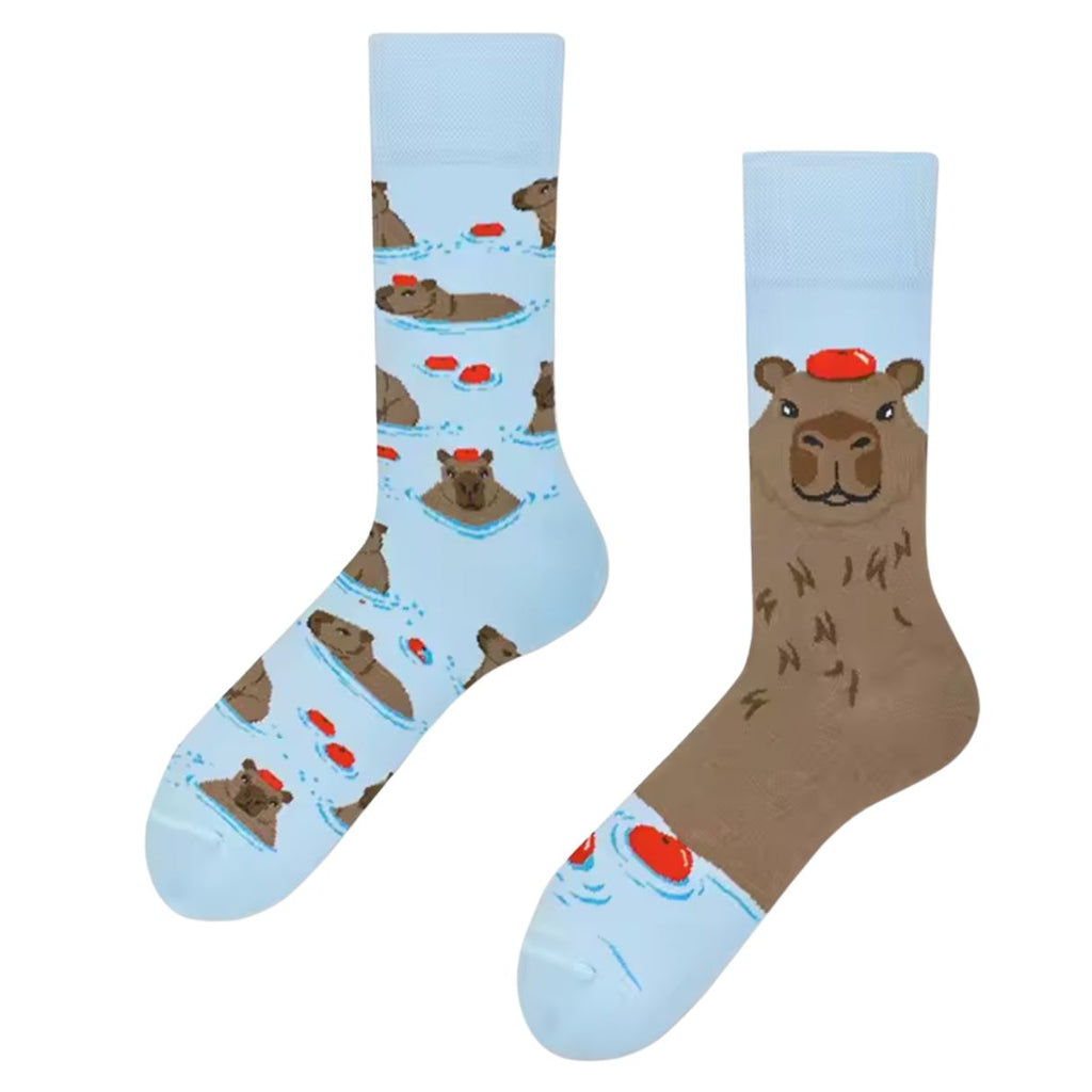 Pair of light blue mismatched socks featuring capybaras in a hot tub—one with a repeated soaking capybara pattern, the other with a large capybara face wearing a red towel.