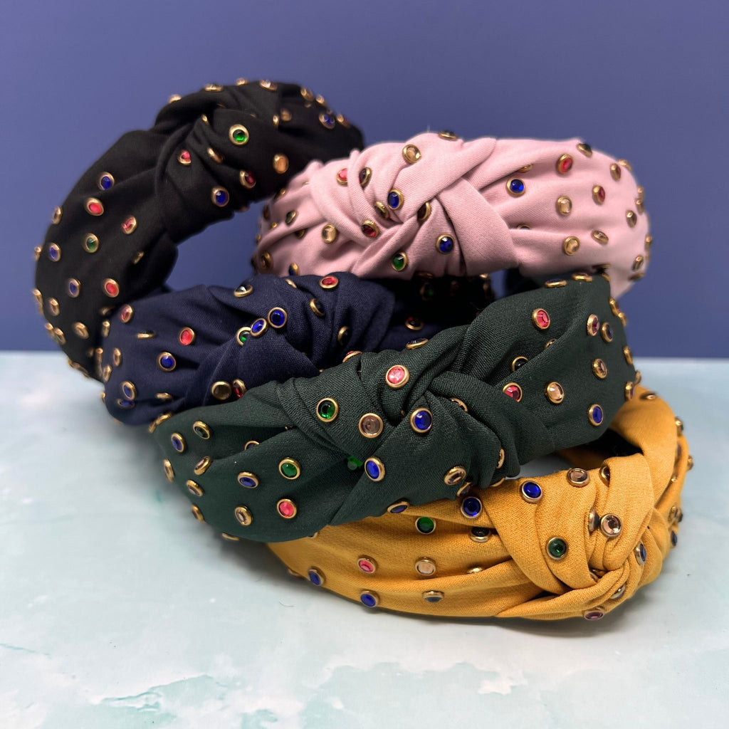 Set of jeweled knotted headbands in yellow, navy, black, pink, cream, and green with multicolor gem studs on soft fabric
