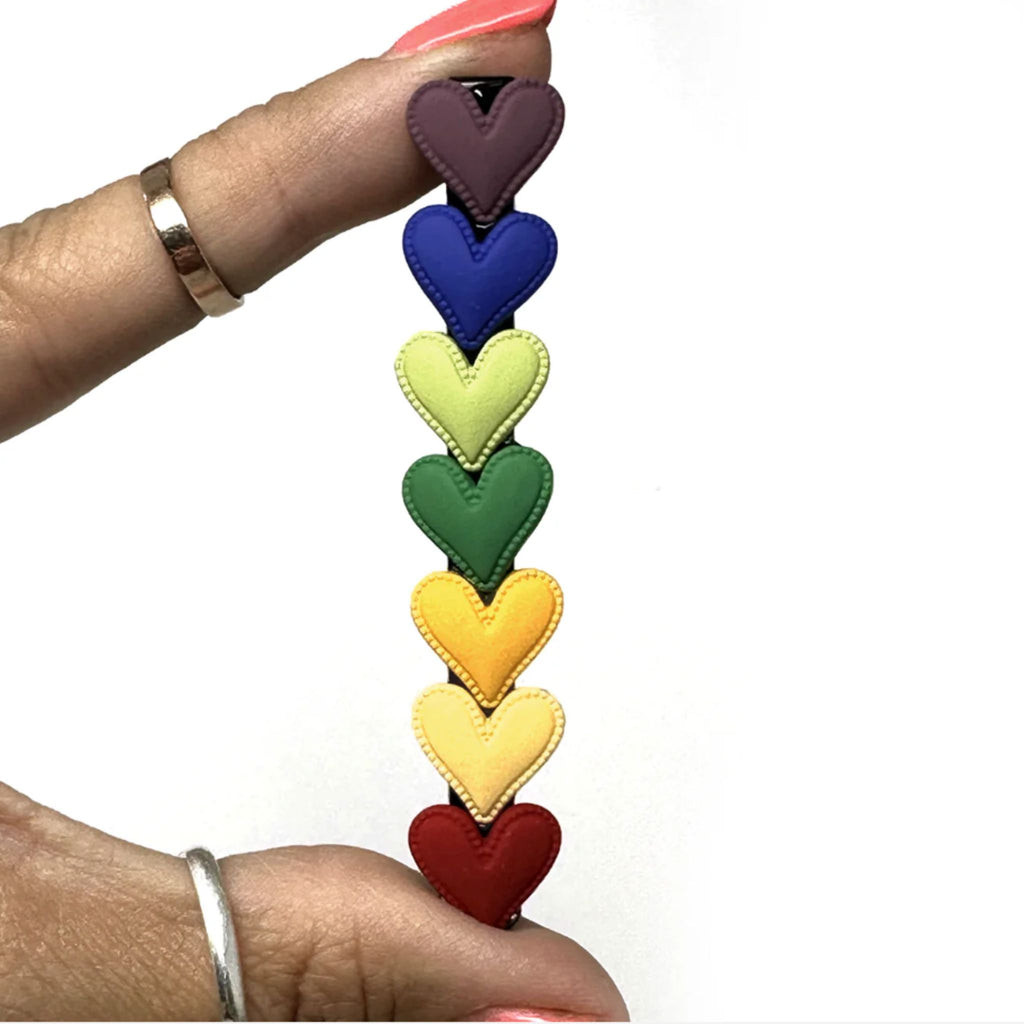 Set of two rainbow heart barrettes measuring approximately 3.5"W x 0.5"H, featuring vibrant multi-color designs with secure clip backing.