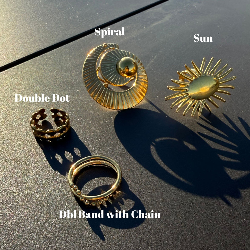 Four gold rings with different designs on a dark surface
