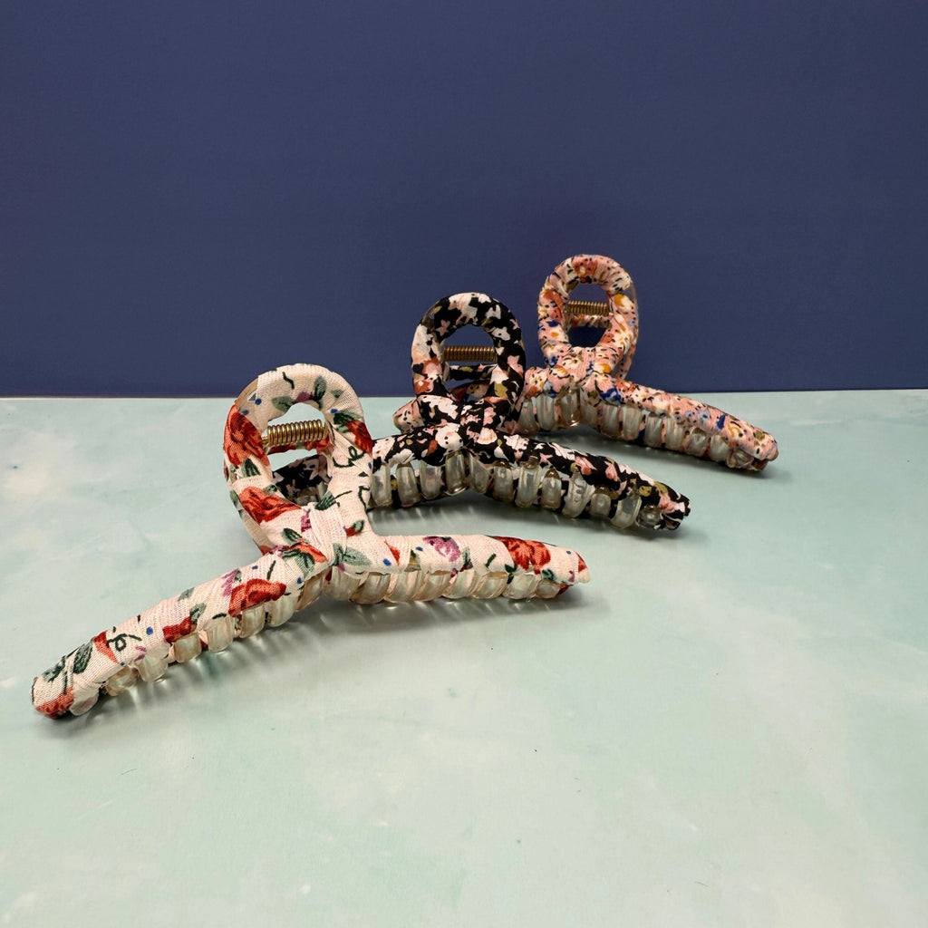 Set of floral-patterned hair clips on a light surface with a dark blue background