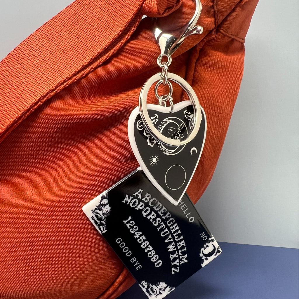 Ouija board and planchette keychain attached to orange bag with silver keyring