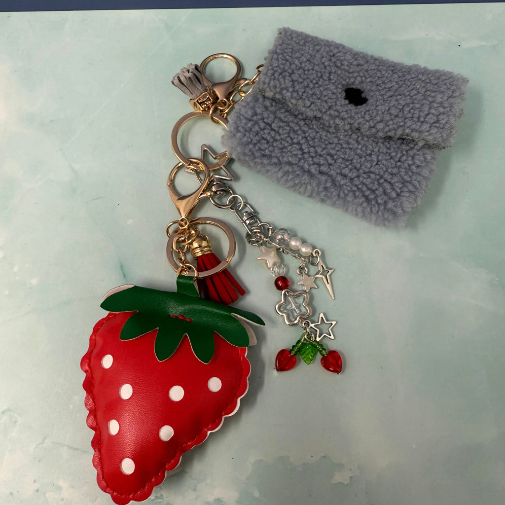 Strawberry charm keychain with fuzzy pouch and star dangle on light background