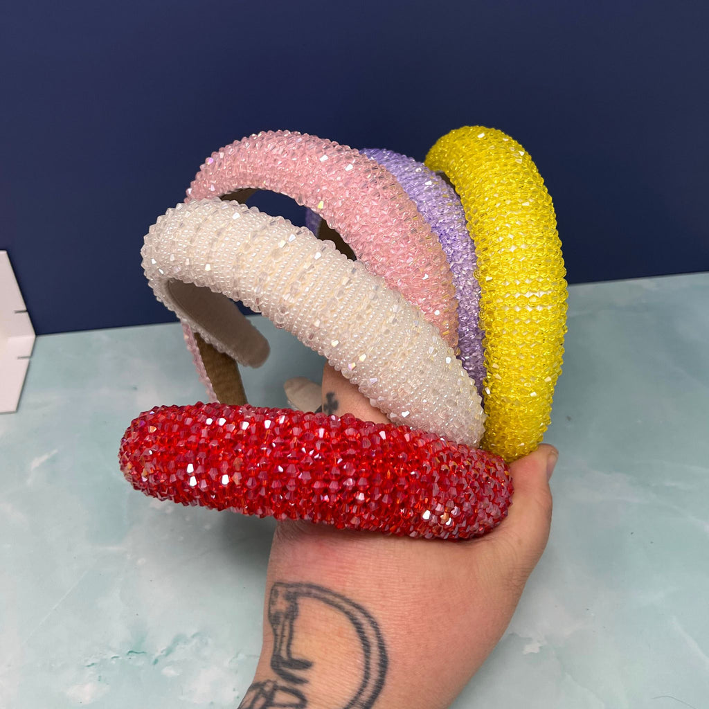 Stack of sparkly crystal beaded headbands in red, white, pink, purple, and yellow on display