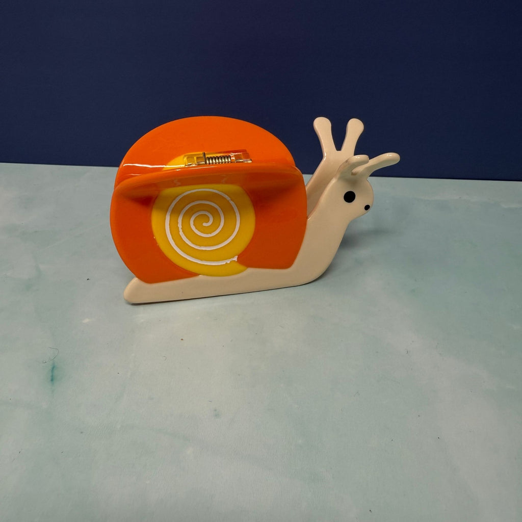 Orange snail hair claw clip with yellow swirl shell, glossy acetate finish, and secure spring grip
