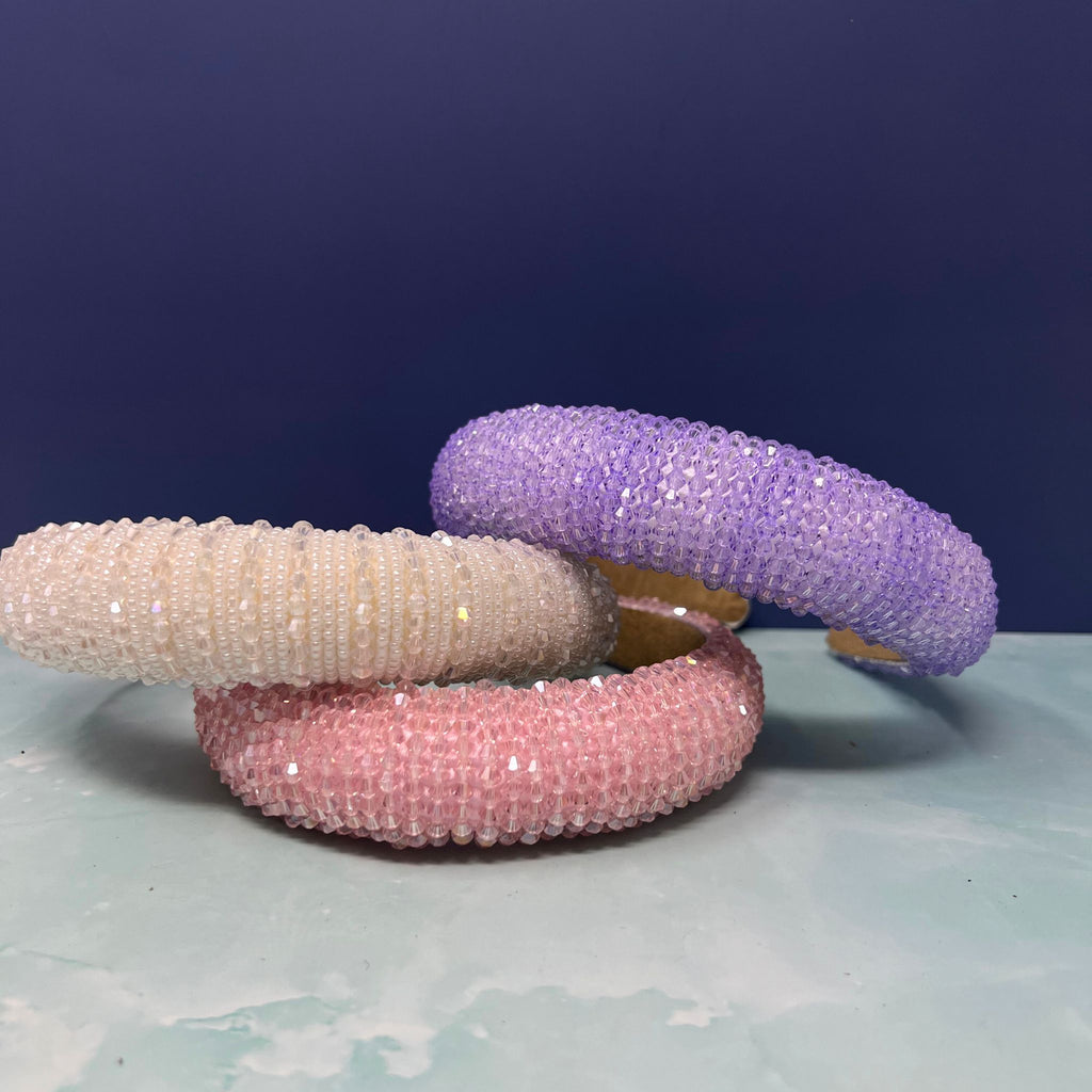 Stack of sparkly crystal beaded headbands in red, white, pink, purple, and yellow on display