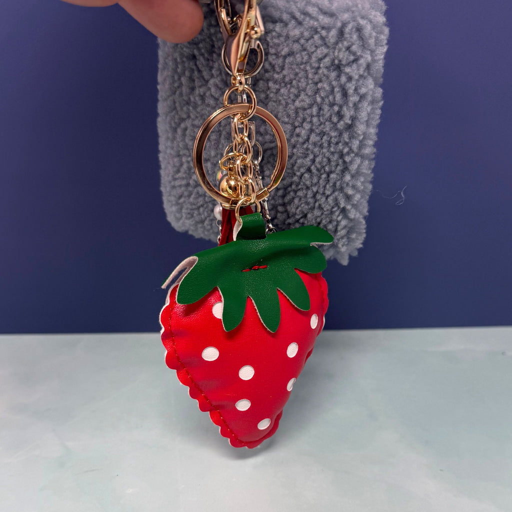 Strawberry charm keychain with fuzzy pouch and star dangle on light background
