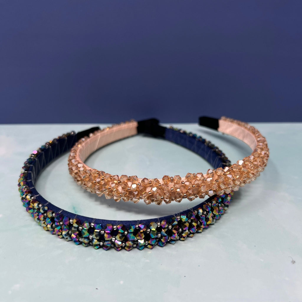 Two beaded headbands, one blue and one multicolored, on a white surface with a blue background.