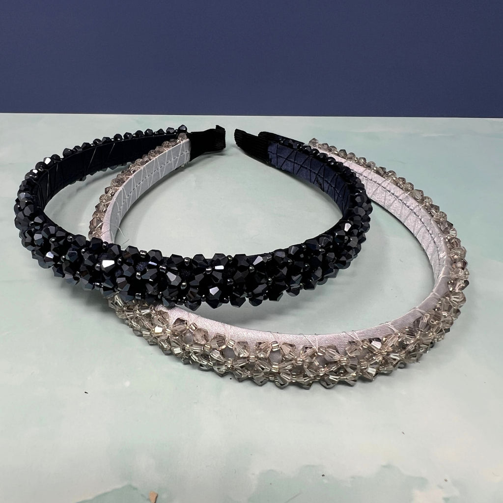Two decorative headbands with black and silver beads on a light blue surface.