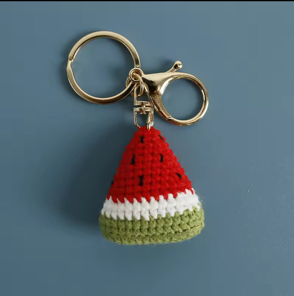 Handmade crochet watermelon keychain with red, white, and green yarn and gold clasp, perfect for bags or keys.