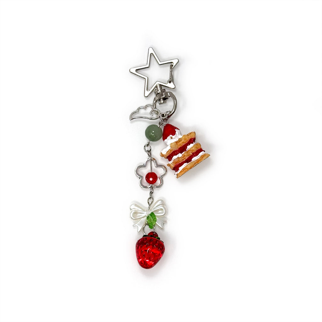 Mini strawberry shortcake keychain with dangling cake slice and strawberry charm on star-shaped clasp.