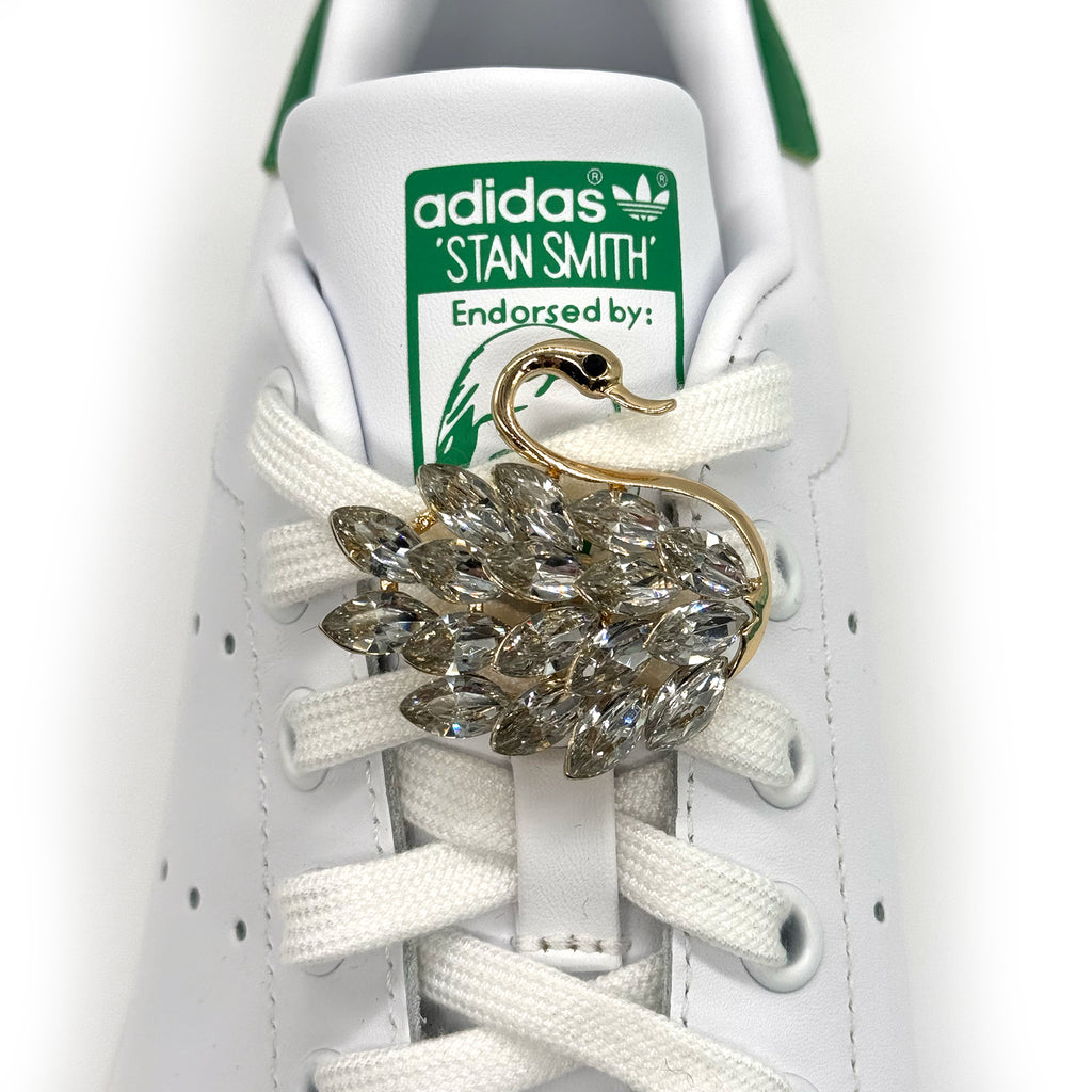 White sneaker with gold swan shoe charm featuring crystal rhinestone wings.