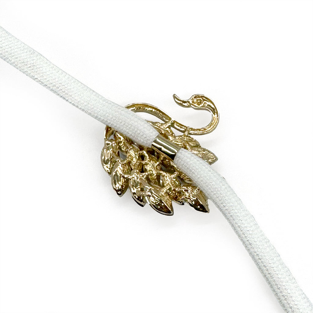 White sneaker with gold swan shoe charm featuring crystal rhinestone wings.